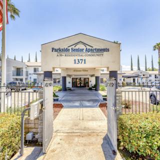 Entrance to Parkside Manor Apartments, featuring a welcoming driveway and palm trees.