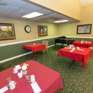 A dining room with tables covered in red tablecloths, decorated with paintings and set for a meal.