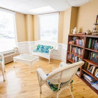 A cozy reading nook with wicker chairs, a small table, and a bookshelf filled with books.