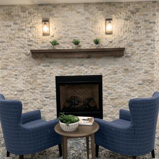 A cozy living room setup with two blue armchairs facing a fireplace, set against a stone wall.