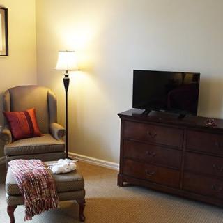 A cozy living room corner with a chair, lamp, and television.