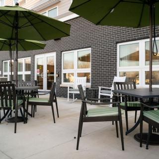 A modern outdoor patio with tables, chairs, and umbrellas set up for dining.