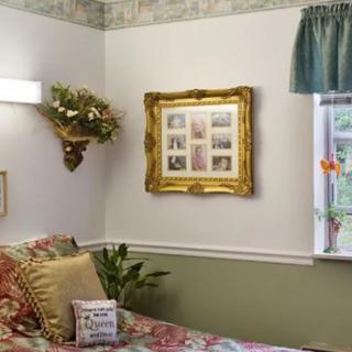 A cozy bedroom featuring floral decor and a golden-framed wall art piece.