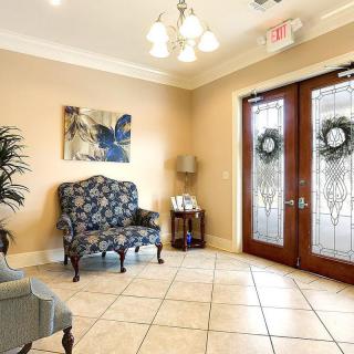 A cozy lobby area featuring elegant armchairs, a decorative painting, and glass double doors adorned with wreaths.