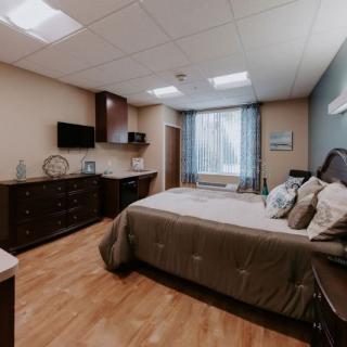 A cozy bedroom with modern furnishings, including a large bed, dresser, and wall-mounted television.