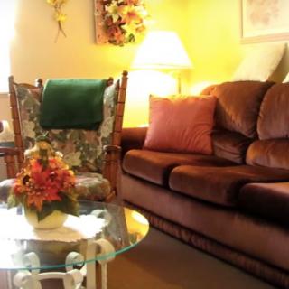 A cozy living room with a brown sofa, floral chair, and a decorated coffee table.