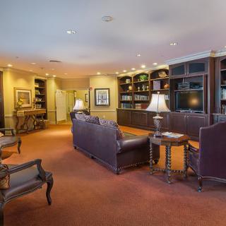 A cozy lounge area with leather seating, bookshelves, and warm lighting.