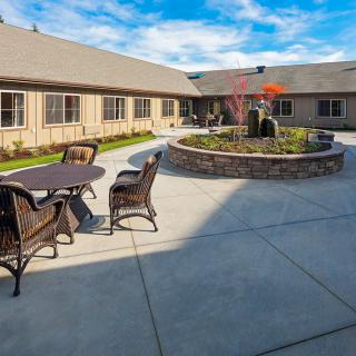 A peaceful courtyard with outdoor seating and a central garden feature on a sunny day.