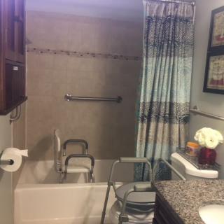 A wheelchair-accessible bathroom with a bathtub, shower curtain, and grab bars.