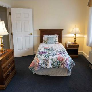A cozy bedroom with a single bed, floral bedding, and warm lighting from table lamps.