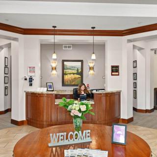 A welcoming reception area with a wooden desk, decorative flowers, and a 'Welcome' sign.