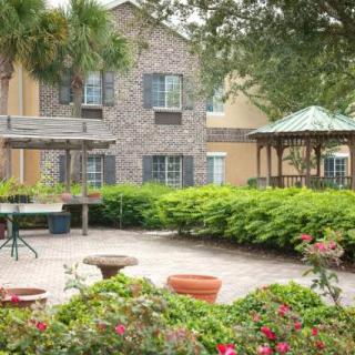 A peaceful courtyard with lush greenery and a gazebo in front of a building.