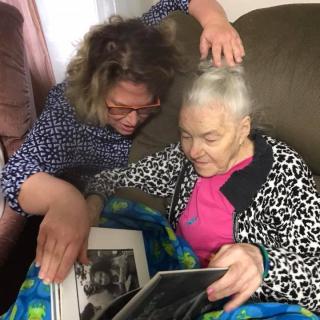 An elderly woman and her caregiver looking through a photo album together, sharing memories.