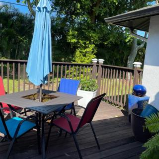 A sunny patio deck with colorful chairs and a blue umbrella, perfect for relaxing outdoors.
