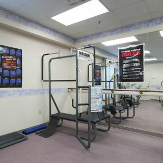 A gym with fitness equipment and mirrors on the wall.