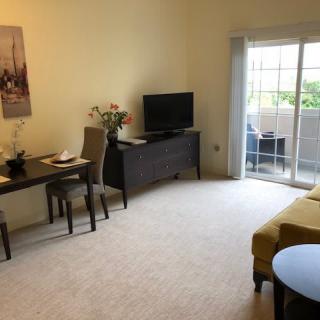 A cozy living room with a dining table, television, and sliding doors leading to a balcony.