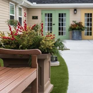 A beautifully landscaped courtyard featuring a bench, vibrant flower arrangements, and colorful doors.