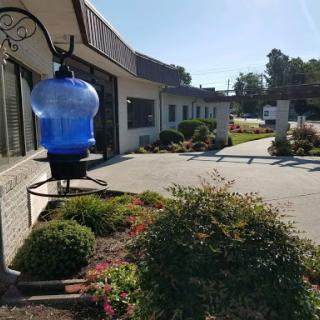 A picturesque view of a building with a blue water container and well-maintained garden on a sunny day.