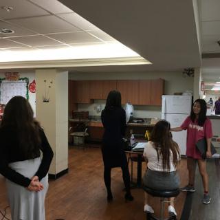 A group of students engaging in conversation in a kitchen-like setting.