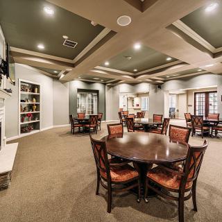 A spacious interior dining area with multiple tables and chairs, featuring elegant lighting and bookshelves.