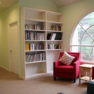 A cozy reading nook with a red armchair and a bookshelf by the window.