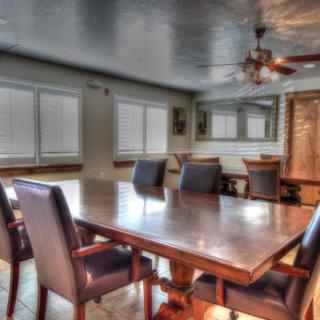 A spacious and well-lit meeting room featuring a large wooden dining table surrounded by comfortable chairs.