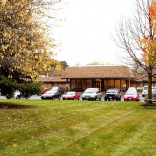 A view of a building with a parking lot surrounded by trees in autumn.