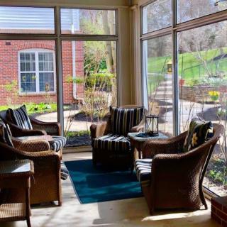 A cozy sunroom with comfortable seating and large windows offering a garden view.