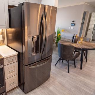 A modern kitchen with a sleek stainless steel refrigerator and a cozy dining area.