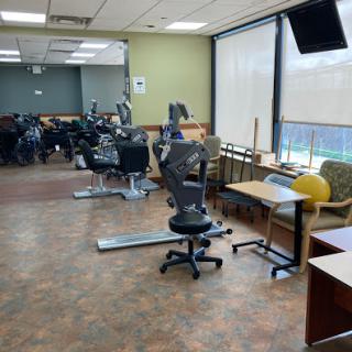 A spacious office area with workstations, chairs, and exercise equipment in the background.
