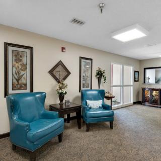 A cozy lounge area with teal chairs, floral decor, and framed artwork on the walls.