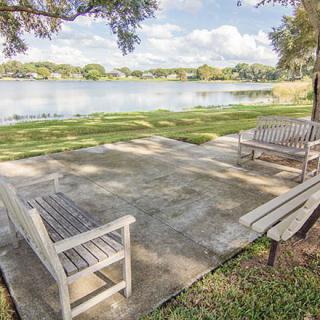 A serene park setting with benches overlooking a peaceful lake.