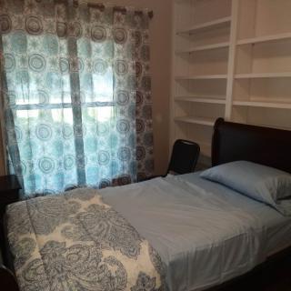 A cozy bedroom with a single bed, patterned curtains, and built-in shelves.