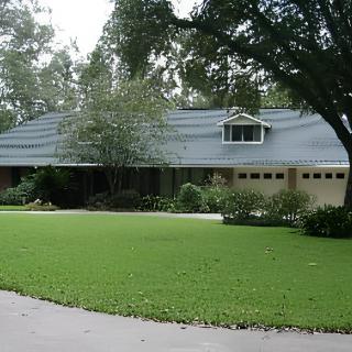 A suburban house with a well-maintained lawn and surrounding trees.
