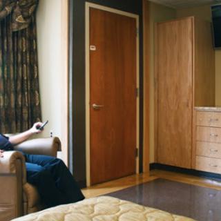 A person relaxing in a cozy hotel room while watching TV.