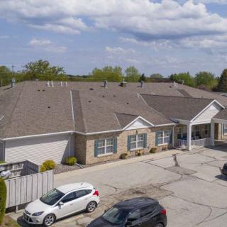 Aerial view of a residential building with a parking lot and cars under a partly cloudy sky.