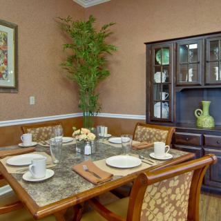 A cozy dining room with a set table, featuring a decorative cabinet and an indoor plant.