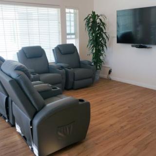 A modern living room with comfortable recliner chairs facing a wall-mounted television.