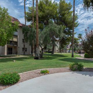 A scenic outdoor view featuring a building surrounded by lush trees and grass, with a clear blue sky overhead.