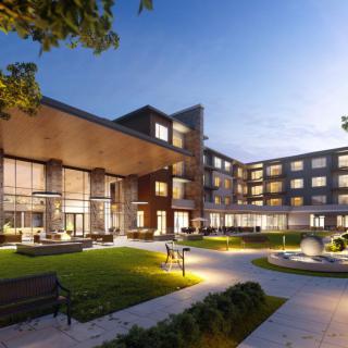 A modern hotel building with illuminated windows and well-maintained landscaping at night.