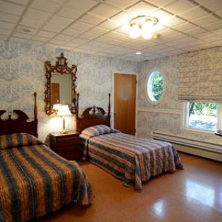 A vintage-style bedroom with twin beds, featuring ornate wallpaper and a decorative mirror.