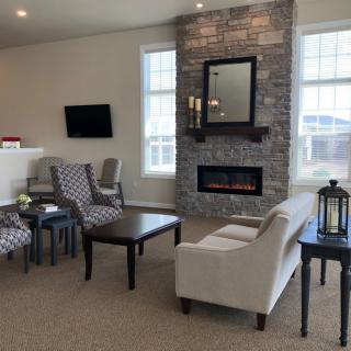 A cozy living room featuring a fireplace, armchairs, a sofa, and a television.