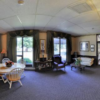 A spacious and inviting lounge area featuring a dining table, comfortable seating, and large windows that let in natural light.
