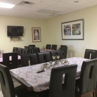 A dining room setup with arranged tables and chairs, featuring wall art and a television.