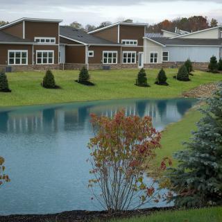 Modern buildings with a landscaped pond and greenery.