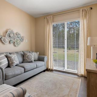 A cozy living room with a comfortable sofa, decorative wall art, and large windows letting in natural light.