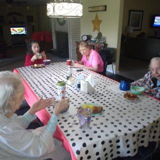 A group of elderly individuals sitting around a table enjoying a meal together indoors.