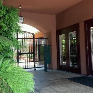 An entrance with a gated archway and lush greenery.