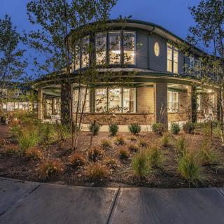 A beautifully lit residential home with modern architecture surrounded by lush landscaping at night.