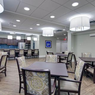 A modern dining area with tables and chairs, featuring a kitchen in the background.